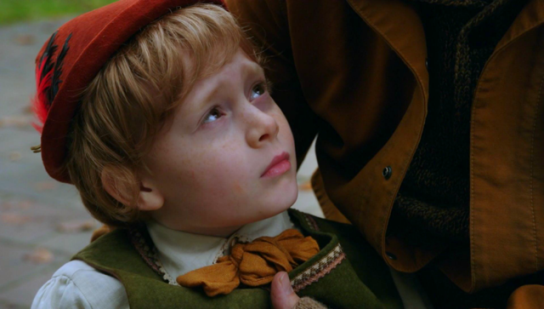 a small blond boy in a red hat and green dungarees looks up fearfully - it's Pinocchio