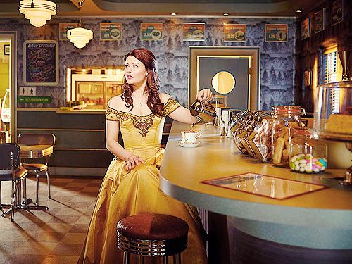 Belle sits at a counter in Granny's diner dressed in an approximation of the golden ballgown that Disney's Belle wears at the end of Beauty and the Beast