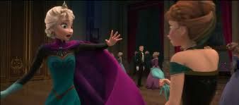 Elsa wears a green bodice and full skirt, with black full length sleeves and a high-colared, long purple cloak held at the neck with a pin. In this shot she has lost one glove but her other hand shows a blue glove that reaches well above the wrist